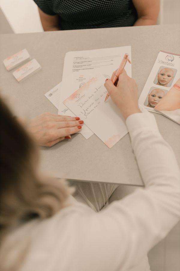 A clinic professional taking notes during a consultation
